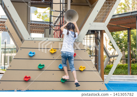 asian little girl climbing playground wall, active childhood and physical development concept 141305782