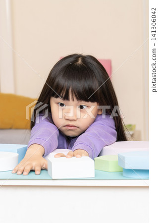 An Asian girl playing with foam blocks indoors. 141306042
