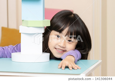 An Asian girl playing with foam blocks indoors. An Asian girl playing with foam blocks indoors. 141306044
