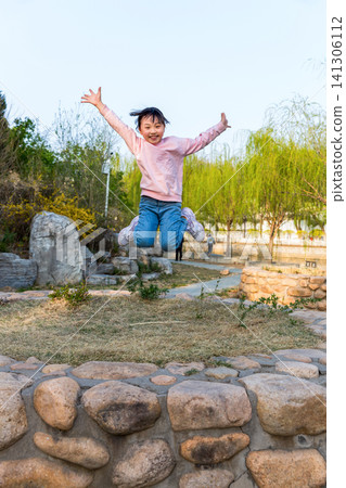 A dynamic shot of a young girl jumping high in the air at a scenic park. 141306112