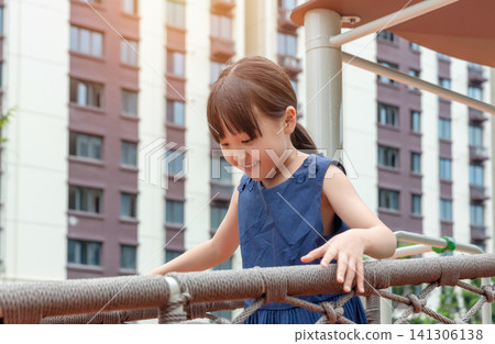 Happy Asian little girl playing on playground equipment, active childhood and outdoor fun concept 141306138