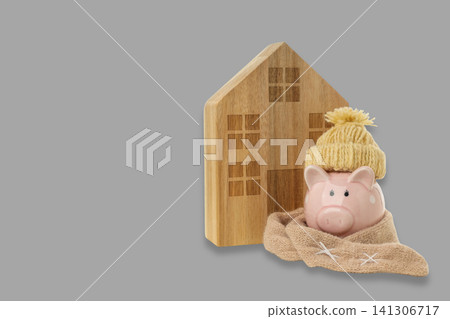 Warm piggy bank by wooden house in heating season Warm piggy bank by wooden house in heating season 141306717