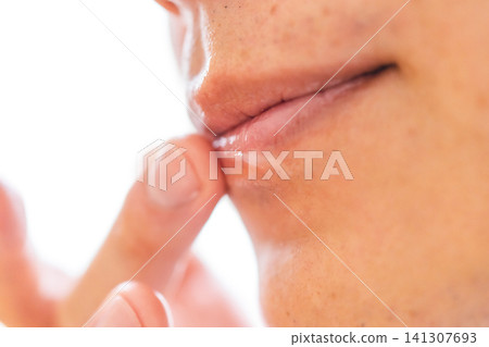 A close-up of a man in his 40s applying lip balm with his finger as part of his lip care routine. A close-up of a man in his 40s applying lip balm with his finger as part of his lip care routine. 141307693