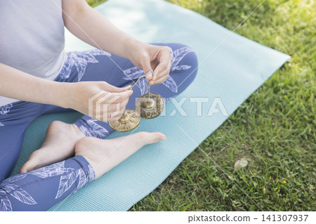 Woman's hands using Tingsha in outdoor yoga Outdoor yoga image 141307937