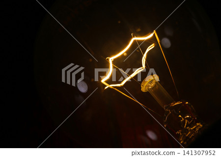 glowing star filament incandescent light bulb illuminated against a dark background. The warm light and vintage filament design create dramatic visual representing innovation, creativity, inspiration glowing star filament incandescent light bulb illuminated against a dark background. The warm light and vintage filament design create dramatic visual representing innovation, creativity, inspiration 141307952