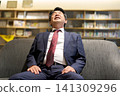 一位商人，工作後筋疲力盡，低頭。 141309296