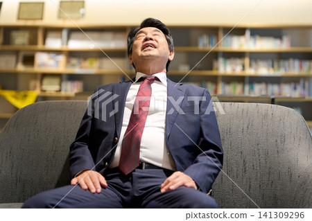 A businessman, exhausted from work and hanging his head. A businessman, exhausted from work and hanging his head. 141309296