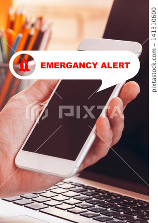 Emergency alert displayed on a smartphone while working at a desk during the day Emergency alert displayed on a smartphone while working at a desk during the day 141310600