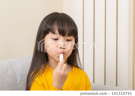 Asian little girl applying lip balm dry lips skincare child healthcare concept Asian little girl applying lip balm dry lips skincare child healthcare concept 141310741