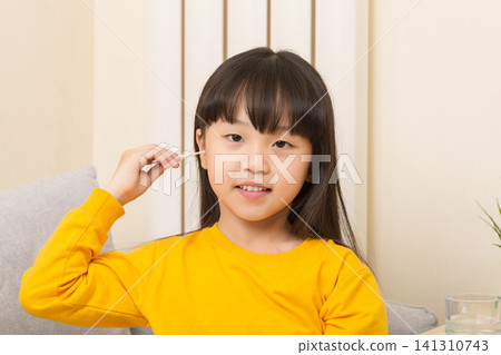Asian girl cleaning ear with cotton swab child hygiene healthcare concept 141310743
