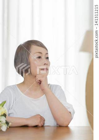 A senior woman tidies herself up while looking in the mirror. A senior woman tidies herself up while looking in the mirror. 141311215