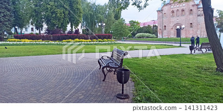 Cozy park alley with benches near ancient Pyatnytska church in Chernihiv Cozy park alley with benches near ancient Pyatnytska church in Chernihiv 141311423