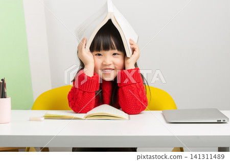 Happy Asian little girl holding book over head, playful learning and study break concept Happy Asian little girl holding book over head, playful learning and study break concept 141311489