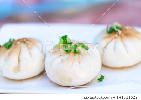 Fresh steamed pork buns topped chopped scallions served white plate Soft fluffy dim sum ready to eat authentic Asian flavor Fresh steamed pork buns topped chopped scallions served white plate Soft fluffy dim sum ready to eat authentic Asian flavor 141311522