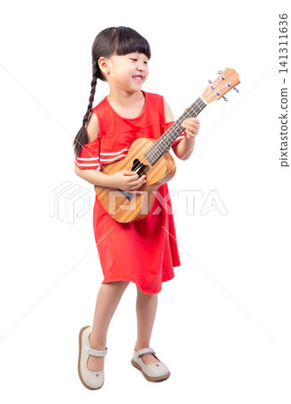 Joyful little girl standing sideways and laughing out loud while strumming a small acoustic ukulele. 141311636
