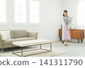 Woman holding a vase in the living room Woman holding a vase in the living room 141311790