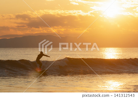 Surfing in the ocean shimmering in the colors of the setting sun at Kugenuma Beach, Shonan. Surfing in the ocean shimmering in the colors of the setting sun at Kugenuma Beach, Shonan. 141312543