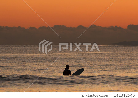 Surfers waiting for waves in the ocean after sunset at Kugenuma Beach, Shonan. Surfers waiting for waves in the ocean after sunset at Kugenuma Beach, Shonan. 141312549
