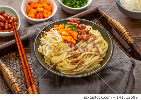 a bowl of traditional Wuhan hot dry noodles with sesame paste, peanuts and pickles on a wooden tray a bowl of traditional Wuhan hot dry noodles with sesame paste, peanuts and pickles on a wooden tray 141312699