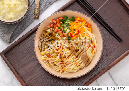 a bowl of traditional Wuhan hot dry noodles with sesame paste, peanuts and pickles on a wooden tray a bowl of traditional Wuhan hot dry noodles with sesame paste, peanuts and pickles on a wooden tray 141312701