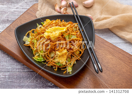 stir-fried Chinese alkaline noodles with cabbage served on a gray plate with a fork, modern food styling. stir-fried Chinese alkaline noodles with cabbage served on a gray plate with a fork, modern food styling. 141312708