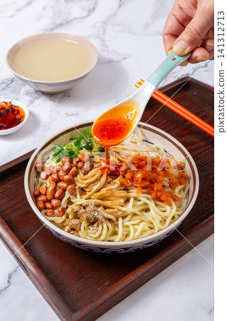 drizzling spicy red chili oil with a spoon onto traditional Wuhan hot dry noodles, high angle view drizzling spicy red chili oil with a spoon onto traditional Wuhan hot dry noodles, high angle view 141312713