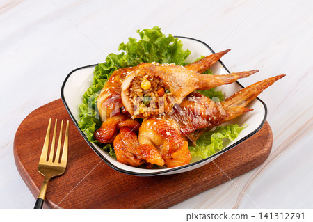 delicious grilled whole chicken wings stuffed with seasoned glutinous rice and vegetables, served on a plate with lettuce. delicious grilled whole chicken wings stuffed with seasoned glutinous rice and vegetables, served on a plate with lettuce. 141312791