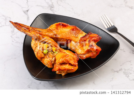 taiwanese style roasted chicken wing stuffed with flavorful fried rice, cut open and served on plate. taiwanese style roasted chicken wing stuffed with flavorful fried rice, cut open and served on plate. 141312794