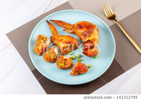 taiwanese style roasted chicken wing stuffed with flavorful fried rice, cut open and served on plate. taiwanese style roasted chicken wing stuffed with flavorful fried rice, cut open and served on plate. 141312795
