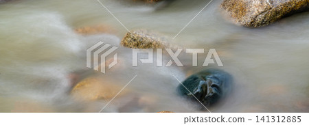 Long exposure shot of smooth flowing river water around large stones with silky effect, nature landscape photography concept Long exposure shot of smooth flowing river water around large stones with silky effect, nature landscape photography concept 141312885