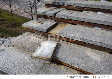 Damaged granite stairs with corroded metal frame in a park, illustrating decay and neglect while emphasizing the need for urgent infrastructure repair in a public urban setting area Damaged granite stairs with corroded metal frame in a park, illustrating decay and neglect while emphasizing the need for urgent infrastructure repair in a public urban setting area 141313596