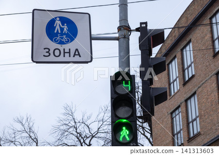 A green pedestrian traffic light with a countdown timer next to a sign designating a shared path for walkers and cyclists to promote road safety and urban traffic navigation flow A green pedestrian traffic light with a countdown timer next to a sign designating a shared path for walkers and cyclists to promote road safety and urban traffic navigation flow 141313603