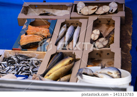Smoked and salted fish sold in cardboard boxes at an outdoor market stall, highlighting traditional seafood retail and local artisan food products for healthy culinary nutrition 141313783