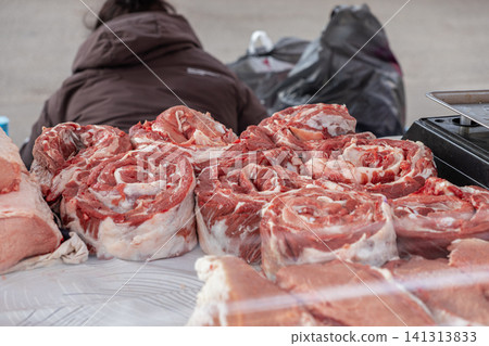 Fresh raw beef rolls displayed on a butcher market table with a seller in the background, capturing a rustic culinary scene for grocery retail, gourmet food preparation and supply Fresh raw beef rolls displayed on a butcher market table with a seller in the background, capturing a rustic culinary scene for grocery retail, gourmet food preparation and supply 141313833