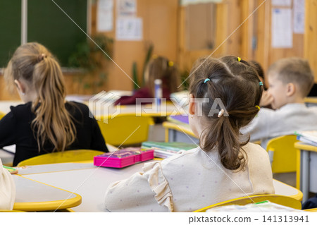 Young students sit at their desks in an elementary school classroom, focusing on daily lessons in a bright, academic environment that promotes childhood development and learning Young students sit at their desks in an elementary school classroom, focusing on daily lessons in a bright, academic environment that promotes childhood development and learning 141313941
