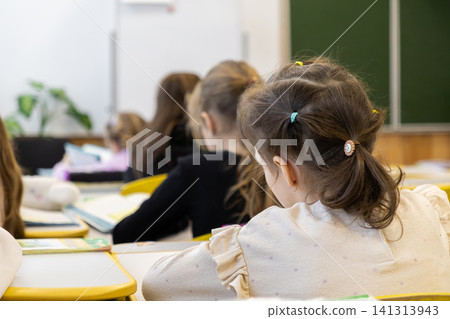 Schoolchildren sitting at desks during a primary school lesson showing focused young students learning together in a classroom environment while participating in daily study sessions Schoolchildren sitting at desks during a primary school lesson showing focused young students learning together in a classroom environment while participating in daily study sessions 141313943