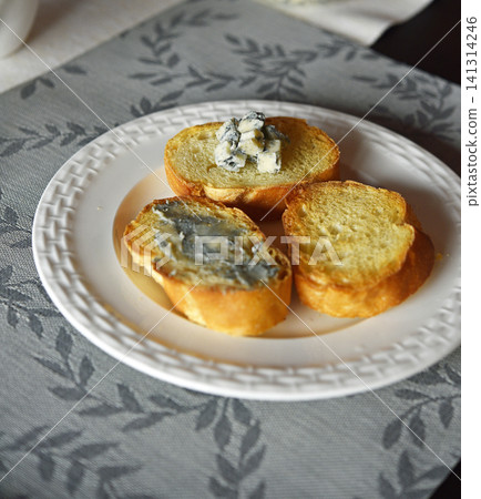 Blue cheese on baguette on white plate. Blue cheese on baguette on white plate. 141314246