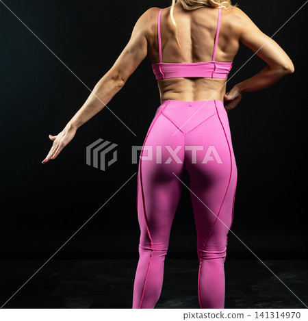 athletic female body in pink sportswear on dark background, fitness woman, athletic girl torso 141314970