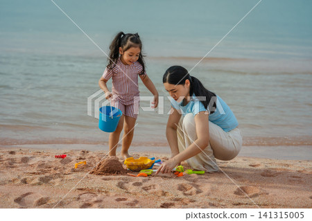 happy preschool child girl playing sand toy with mother on sea beach in Pattaya, Thailand happy preschool child girl playing sand toy with mother on sea beach in Pattaya, Thailand 141315005