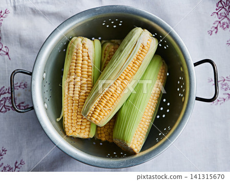Closeup, corn or maize on table for raw fruit, wellness or healthy nutrition in home meal or kitchen. Cobs, background or above of natural produce for organic food, fiber or vitamin b in lunch diet Closeup, corn or maize on table for raw fruit, wellness or healthy nutrition in home meal or kitchen. Cobs, background or above of natural produce for organic food, fiber or vitamin b in lunch diet 141315670