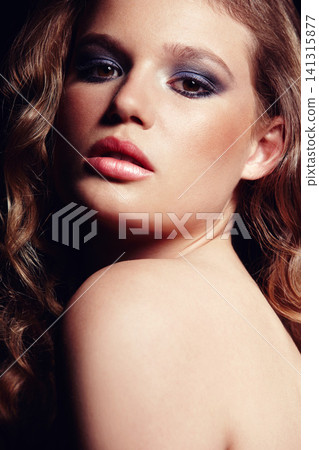 Portrait, woman and makeup on face in studio with bright eyeshadow, sensual lips and wavy hair for beauty. Confident, female person and cosmetics, skincare and self love for glowing healthy skin 141315877