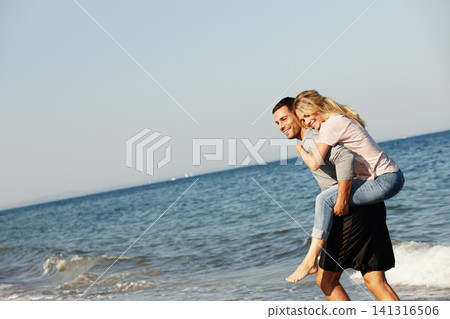 Couple, ocean waves and piggyback on vacation, smile and peace at beach or game by blue sky. People, happy and tropical island for bonding on weekend, outdoor nature and love for marriage or romance Couple, ocean waves and piggyback on vacation, smile and peace at beach or game by blue sky. People, happy and tropical island for bonding on weekend, outdoor nature and love for marriage or romance 141316506