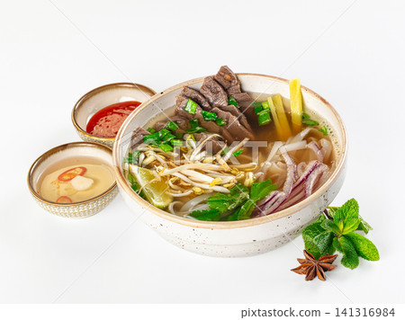 Bowl of pho bo with beef slices, rice noodles, herbs, bean sprouts, lime, and condiments on white background Bowl of pho bo with beef slices, rice noodles, herbs, bean sprouts, lime, and condiments on white background 141316984