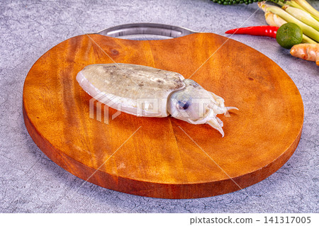 Fresh cuttlefish on wooden cutting board with chili lime and herbs Fresh cuttlefish on wooden cutting board with chili lime and herbs 141317005