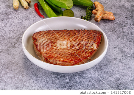 Grilled tuna steak in white bowl with fresh herbs and spices on gray surface 141317008