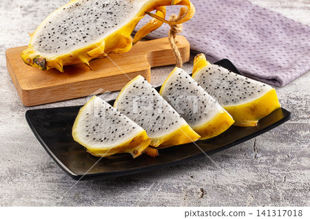 Sliced yellow dragon fruit on black plate with wooden cutting board Sliced yellow dragon fruit on black plate with wooden cutting board 141317018