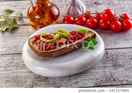 Grilled eggplant with sun dried tomatoes and leek slices on white plate Grilled eggplant with sun dried tomatoes and leek slices on white plate 141317060