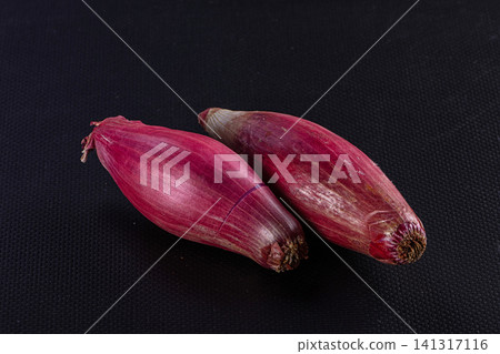 Two red onions on black textured background 141317116
