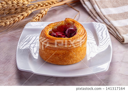 Cherry pastry on white plate with wheat stalks and striped cloth Cherry pastry on white plate with wheat stalks and striped cloth 141317164