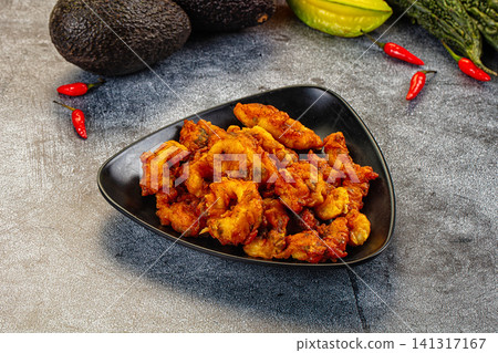 Crispy fried seafood on black plate with avocado and chili peppers Crispy fried seafood on black plate with avocado and chili peppers 141317167